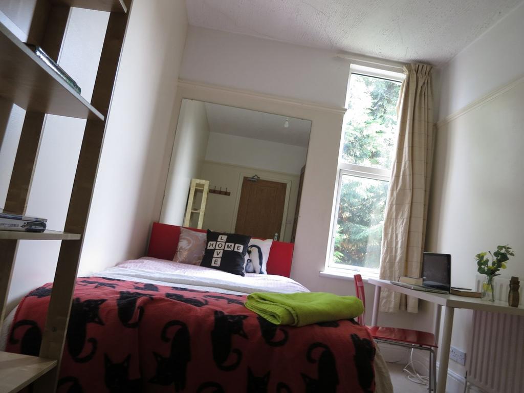 A well-lit bedroom featuring a large bed with v...