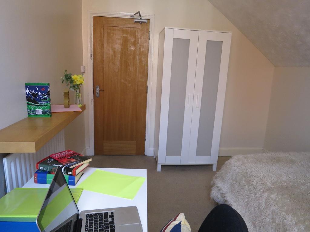 A cozy student bedroom featuring a wooden door,...