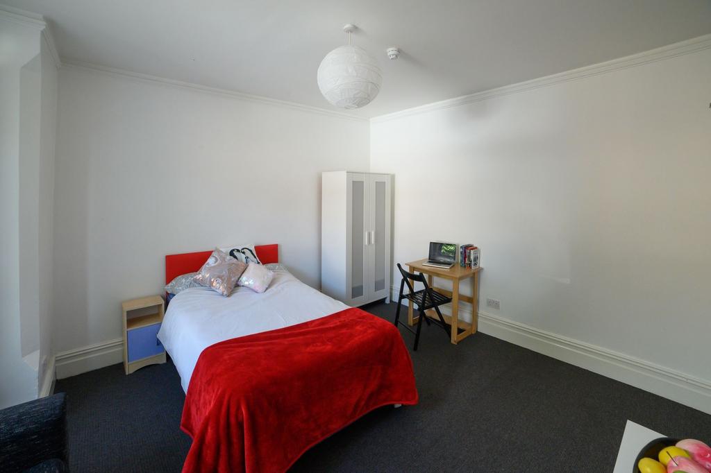 A bright and welcoming bedroom featuring a comf...