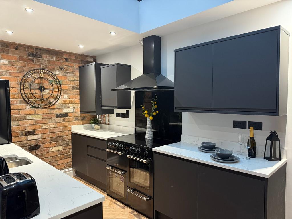 Modern, stylish kitchen featuring dark cabinetr...