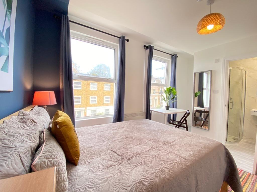 A bright, well-lit bedroom featuring a cozy bed...