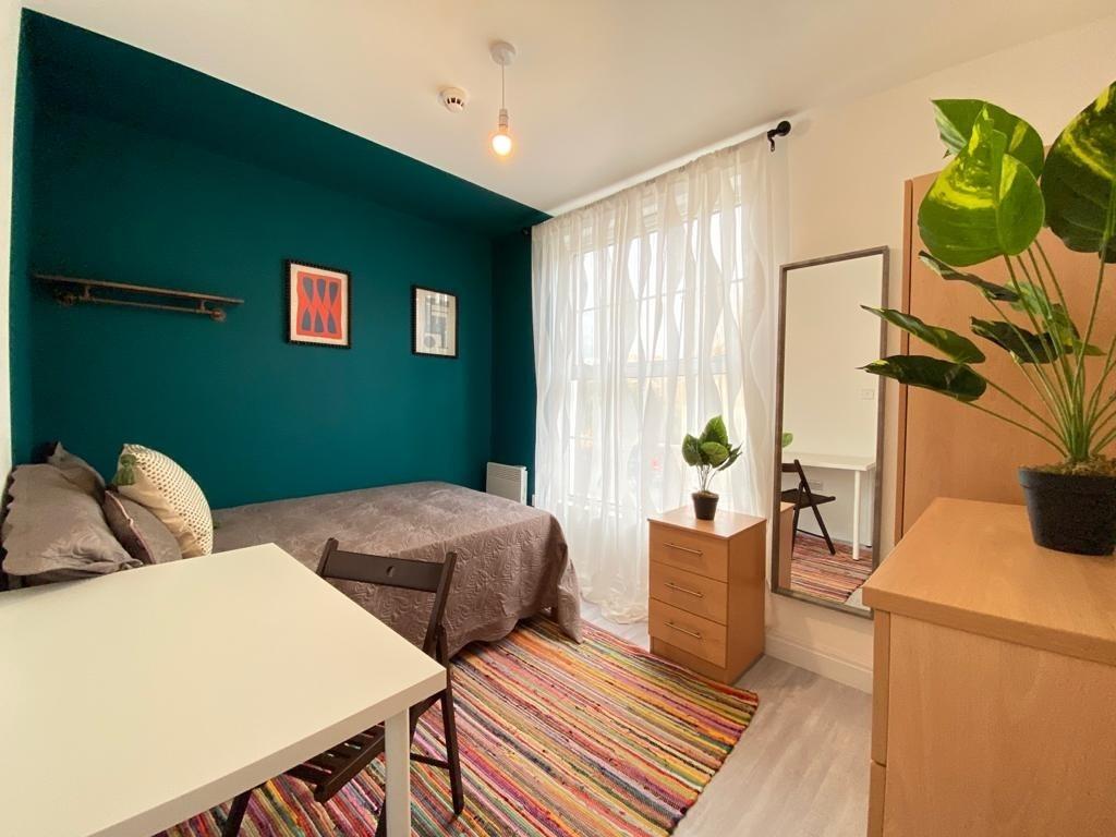 A bright and welcoming bedroom featuring a cozy...
