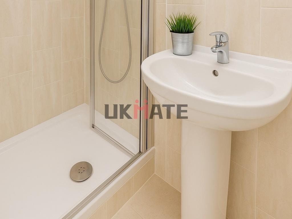 Clean and bright bathroom featuring a shower ar...