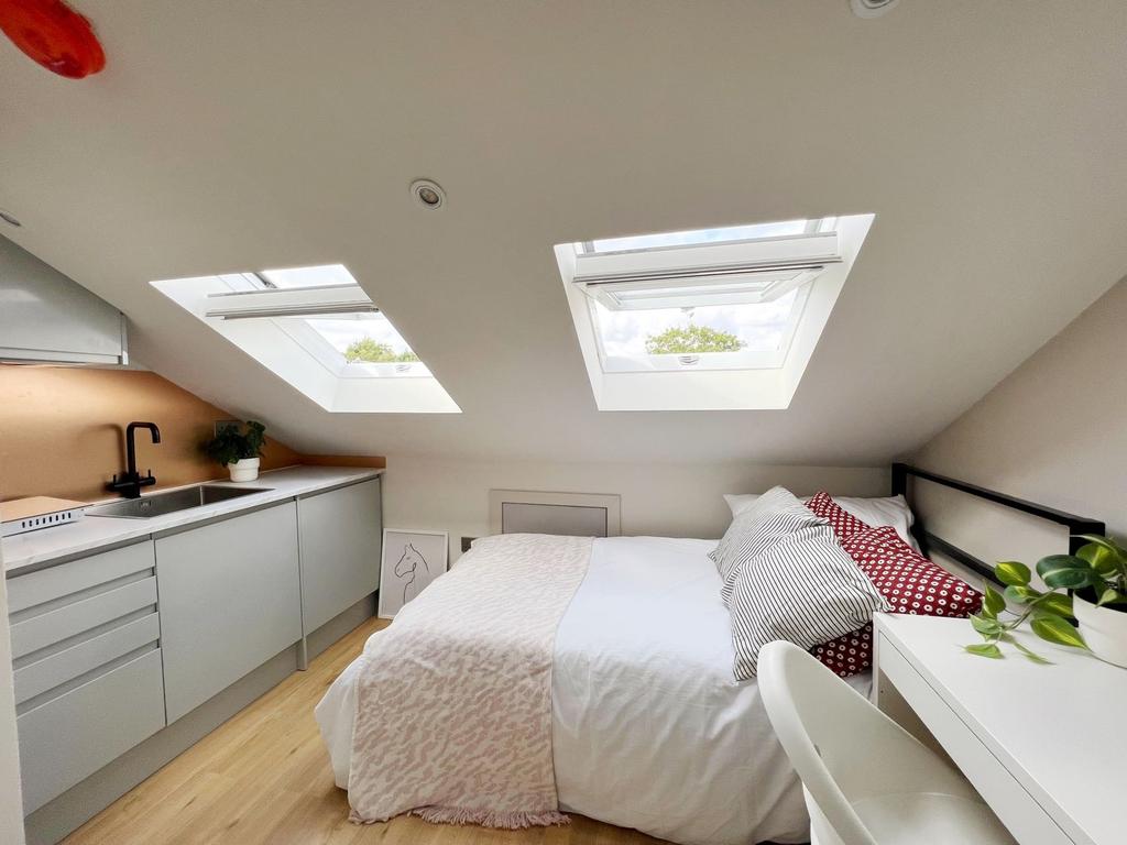 Bright and cozy attic bedroom featuring two sky...