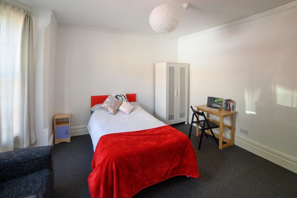 A cozy single bedroom featuring a neatly made b...