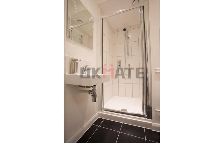 A modern, clean bathroom featuring a glass-encl...