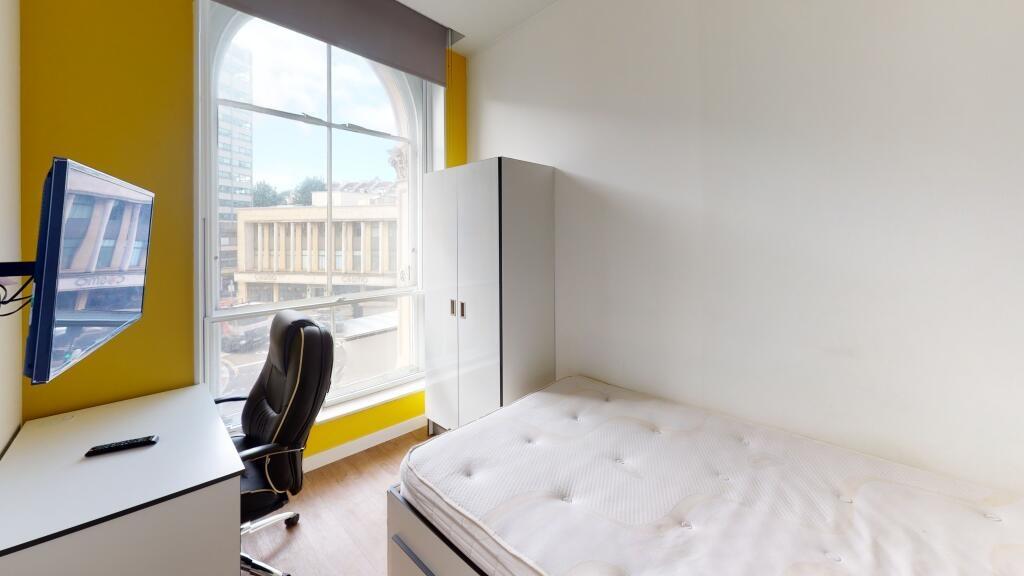 A bright and tidy bedroom featuring a comfortab...