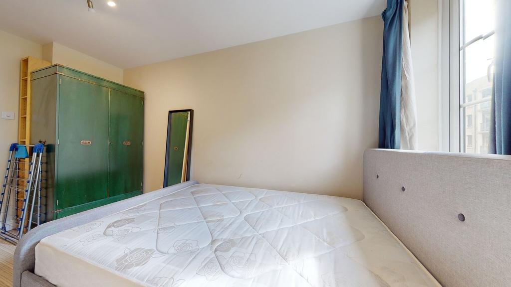 This well-lit bedroom features a comfortable be...