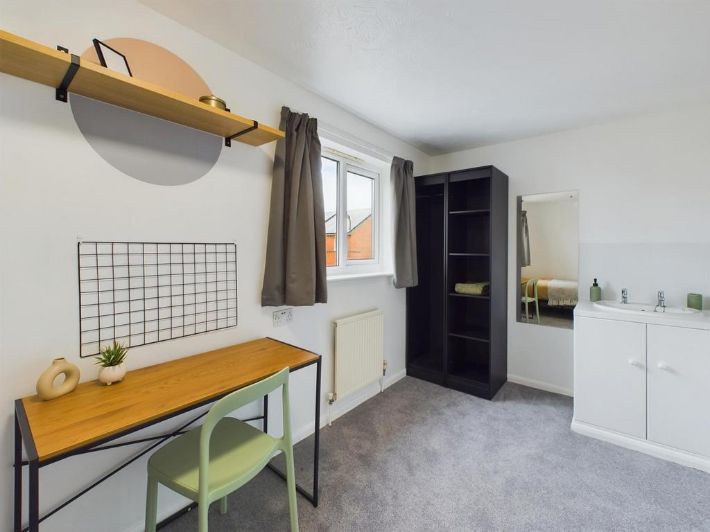 A bright and tidy double bedroom with a workspa...