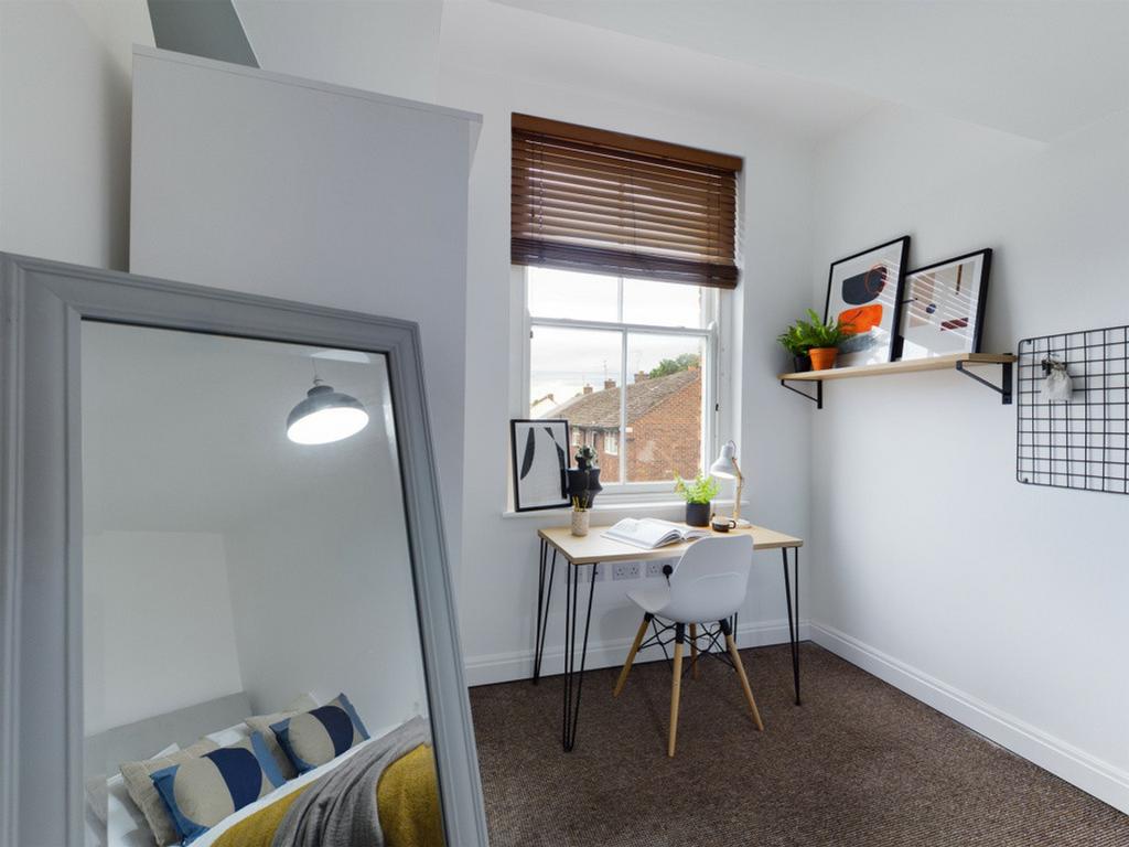 A bright and tidy double bedroom with a cozy de...