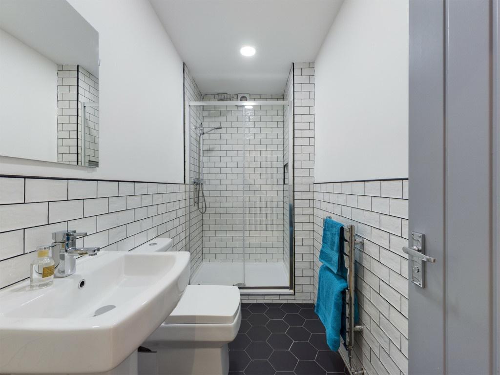 A modern, tidy bathroom featuring a walk-in sho...