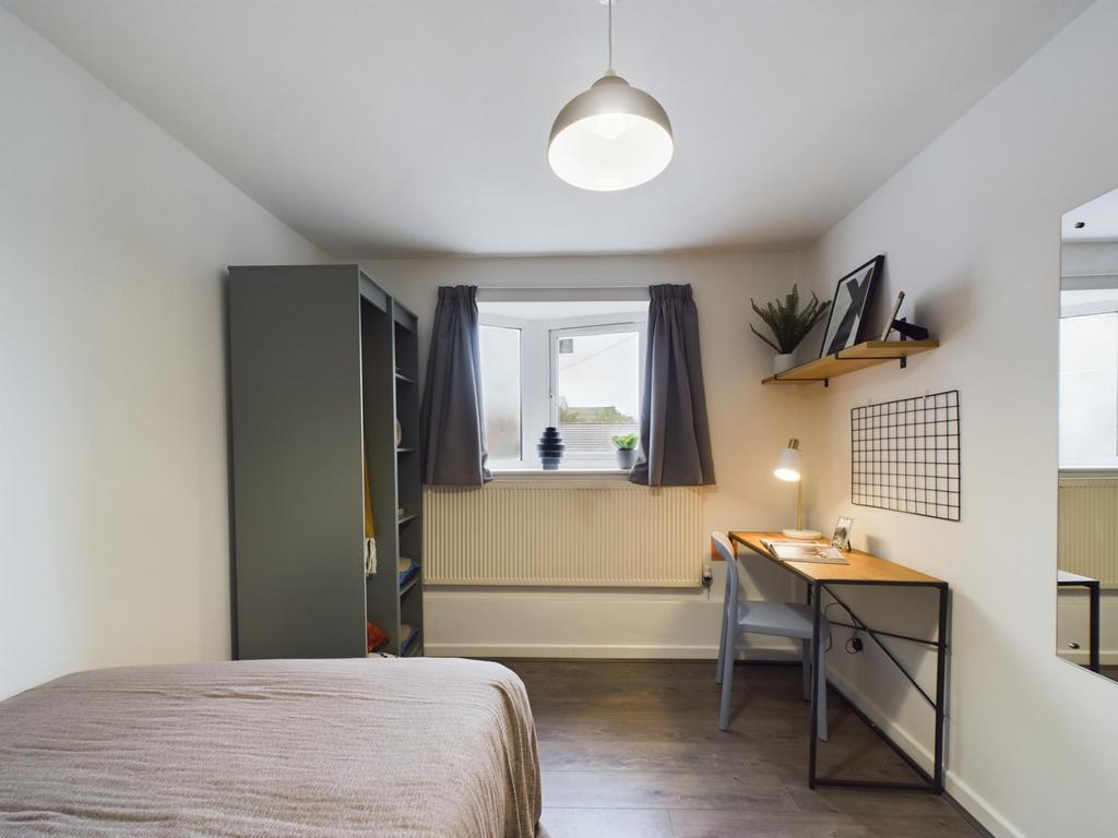 A bright and clean bedroom featuring a neatly m...