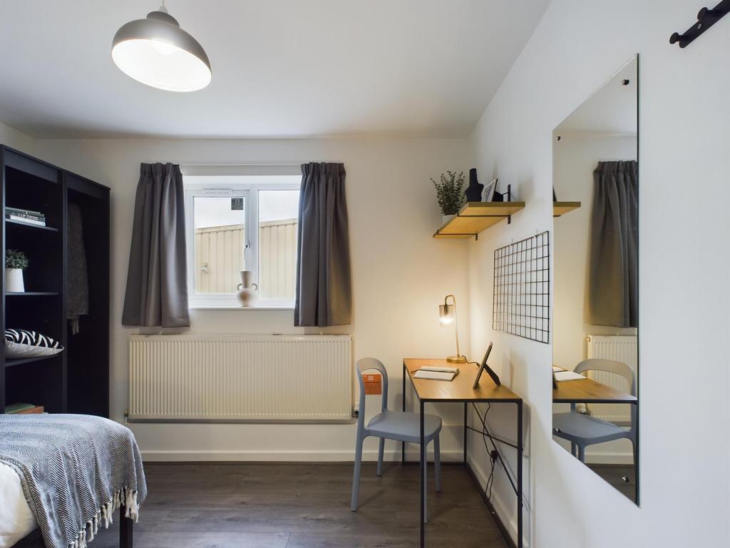 A bright and tidy bedroom featuring a bed, desk...