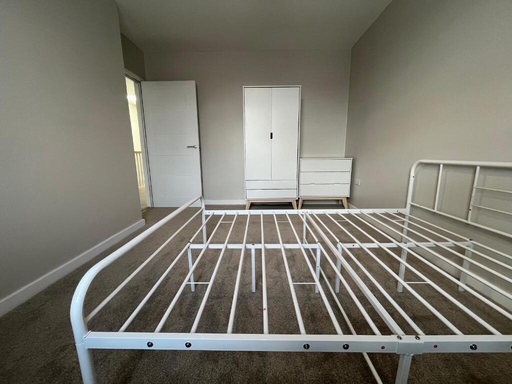 A bright and airy bedroom with a white metal be...