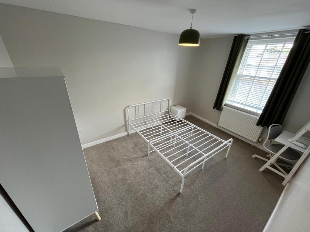 A bright, airy bedroom with a metal bed frame a...