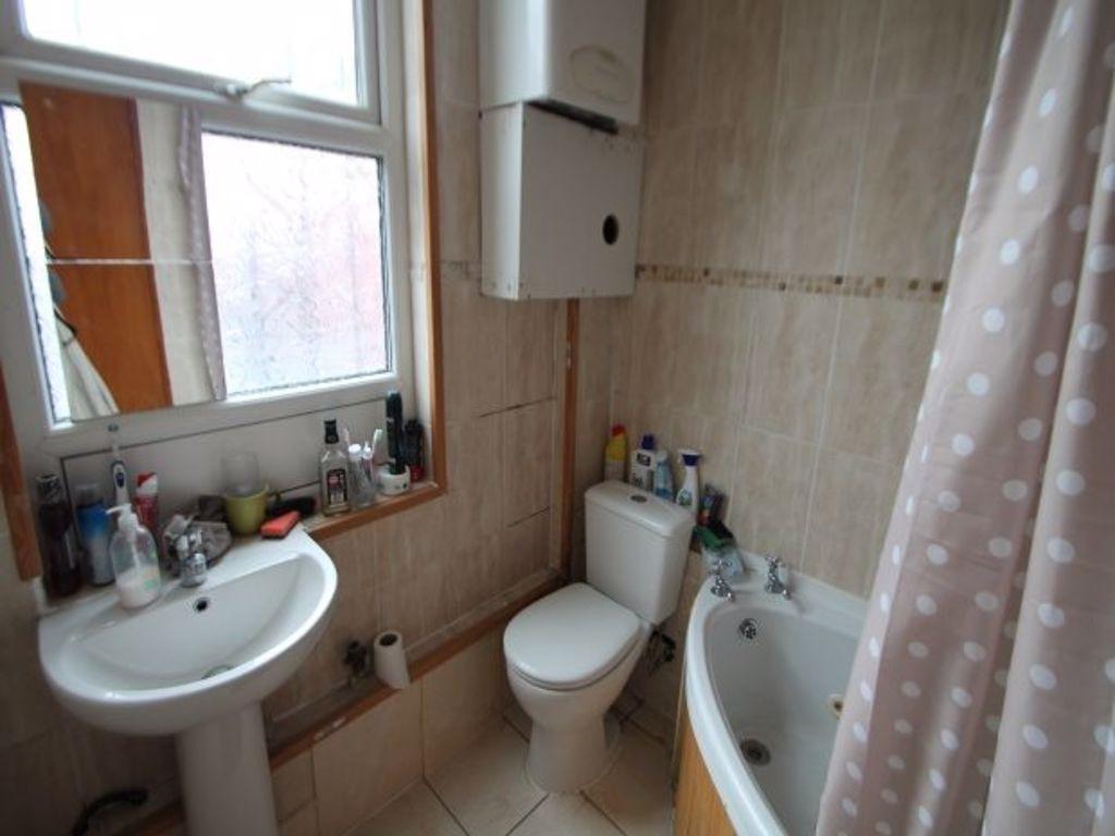 A compact bathroom featuring a corner bathtub w...