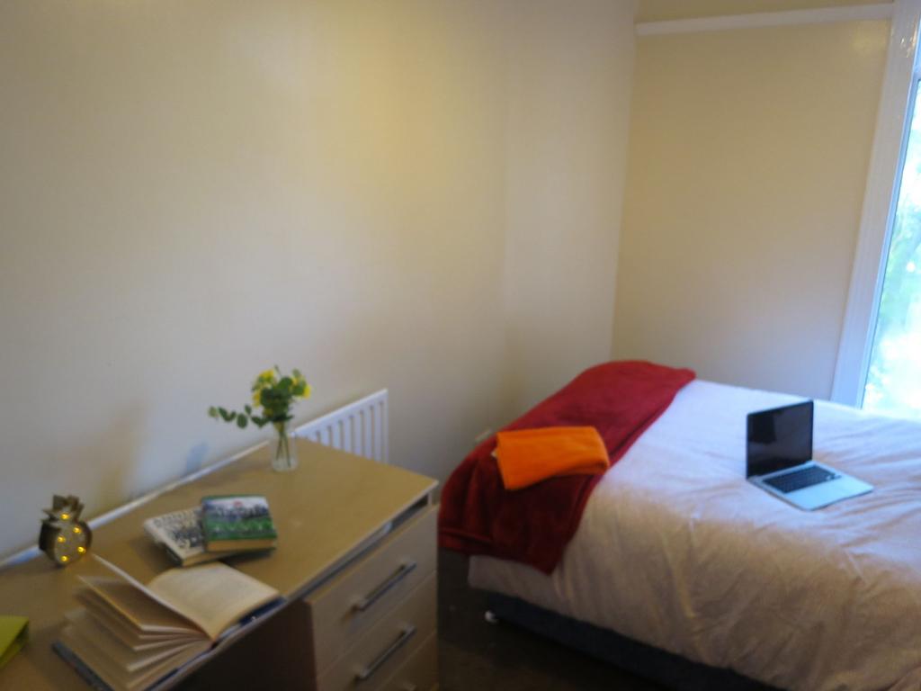 A cozy single bedroom featuring a neatly made b...