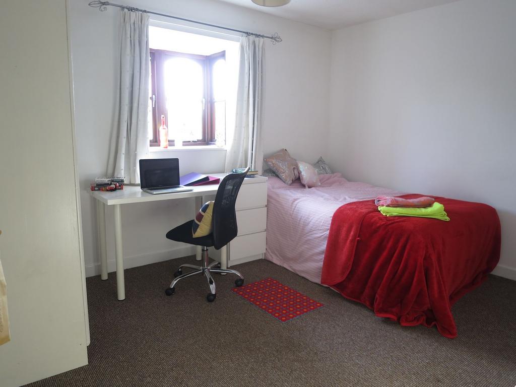 A cozy single bedroom featuring a bed with pink...