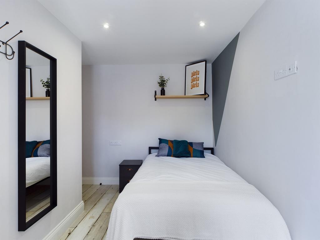 A bright and tidy single bedroom featuring mode...