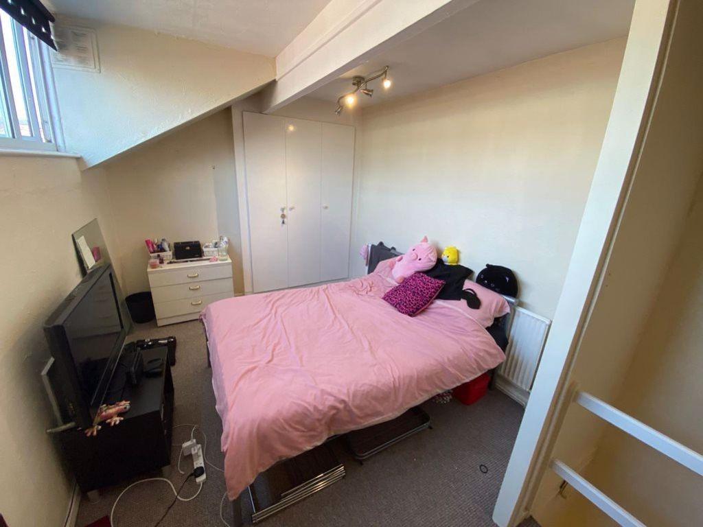 A cozy bedroom featuring a double bed with pink...