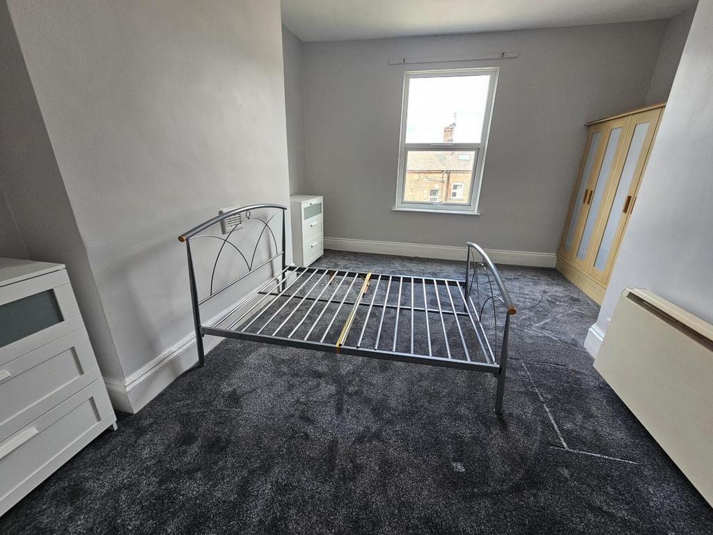 A bright and tidy bedroom featuring a metal bed...