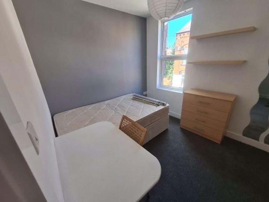 A cozy, well-lit single bedroom featuring a bed...
