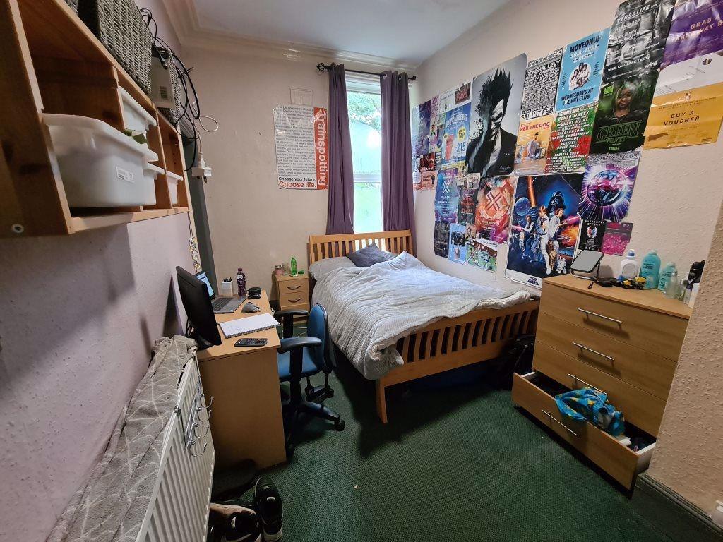 A cozy single bedroom with a comfortable wooden...