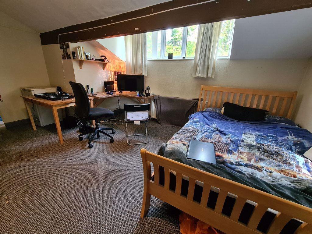 A cozy double bedroom featuring a wooden bed wi...
