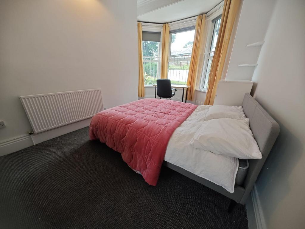 A bright double bedroom featuring a large windo...