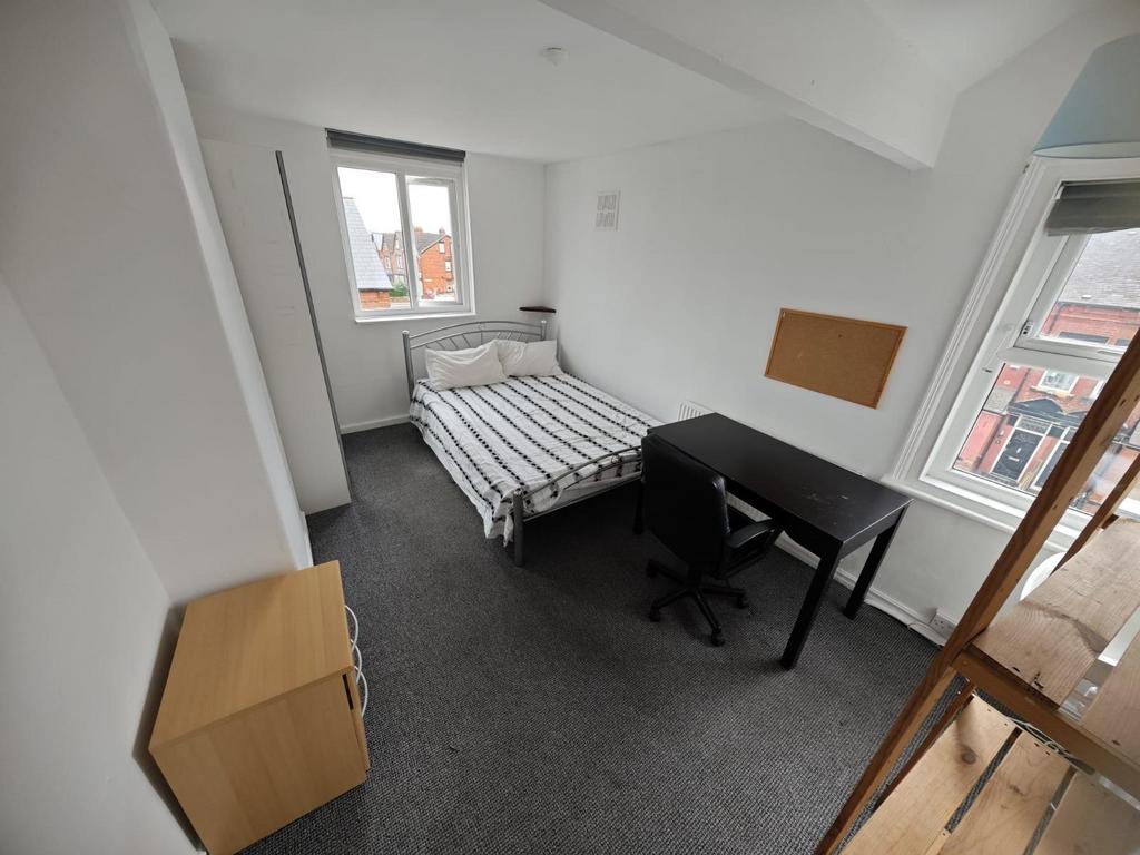 A neat single bedroom featuring a bed with stri...