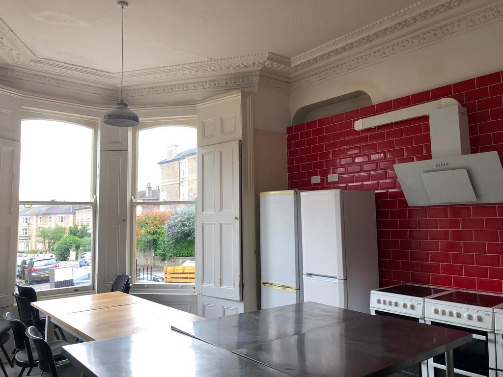 A spacious kitchen with red tiled walls, large ...