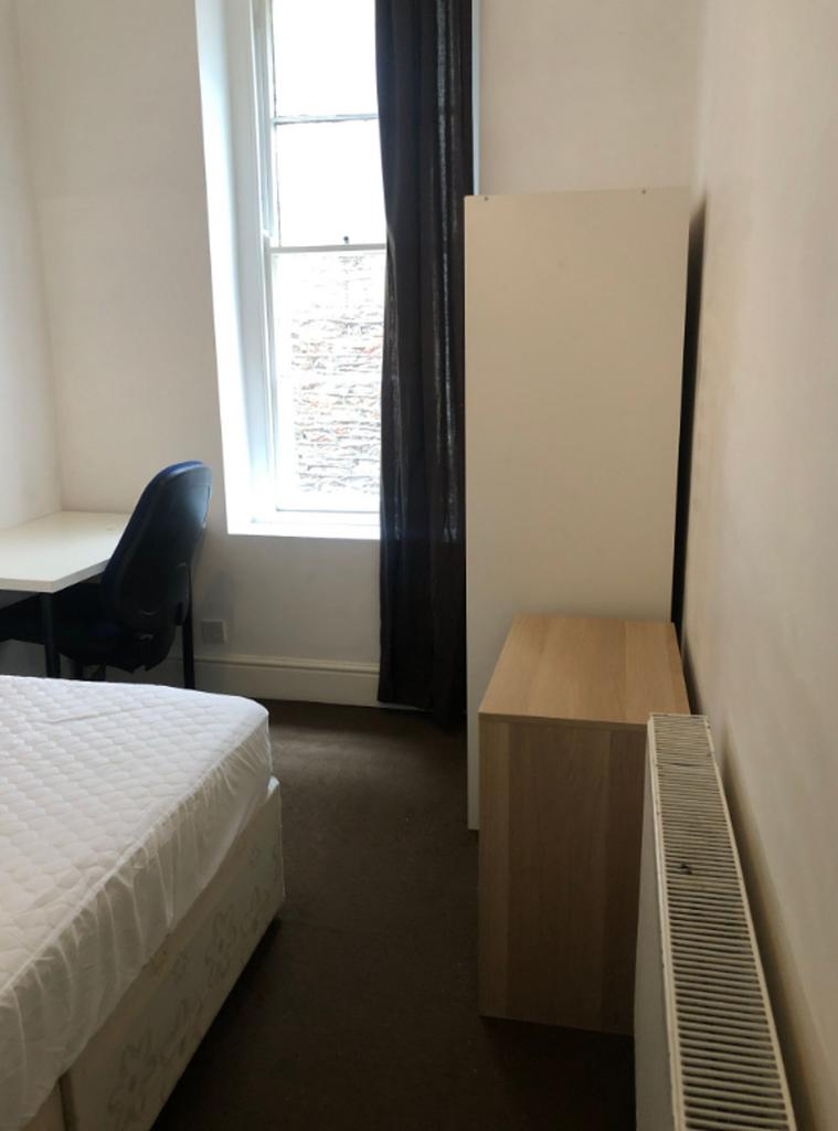 A tidy double bedroom with a desk and chair, fe...