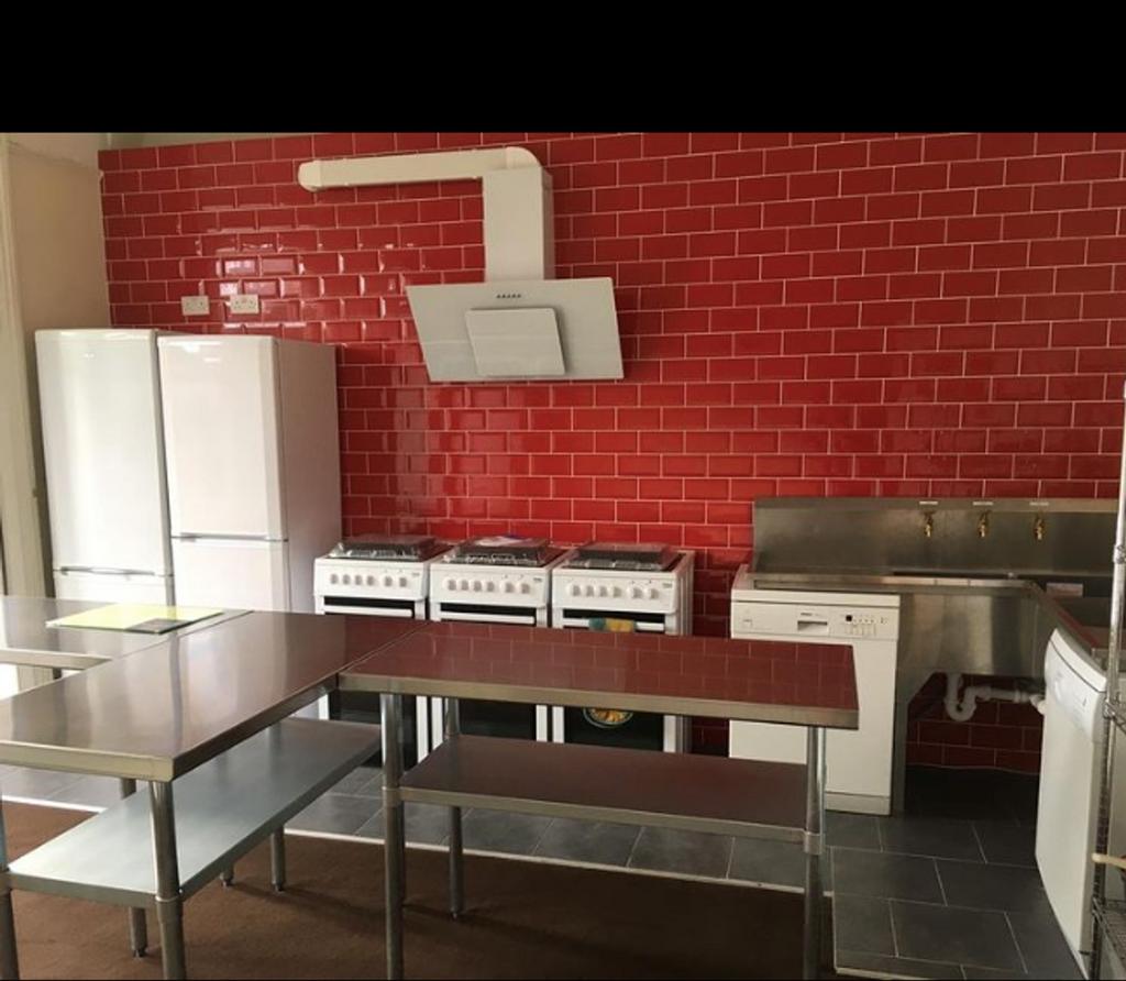 A modern kitchen with red tiled walls and stain...