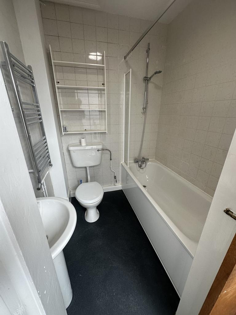A compact bathroom featuring a standard bathtub...