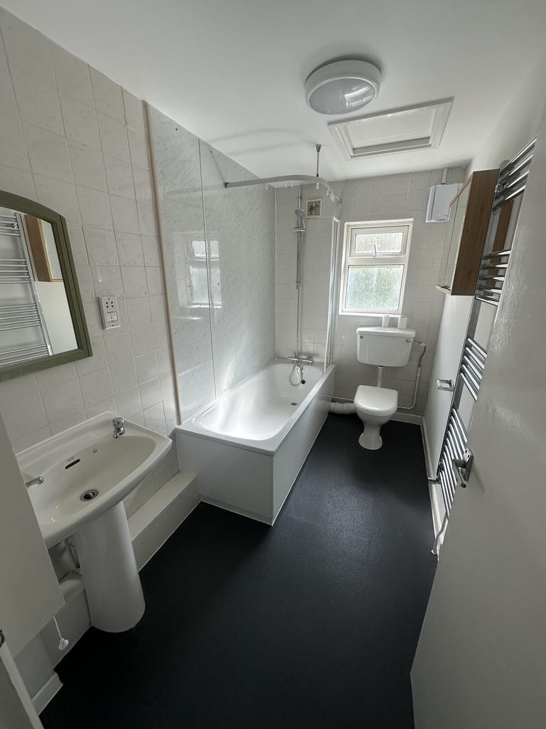 Bright and clean bathroom featuring a bathtub w...