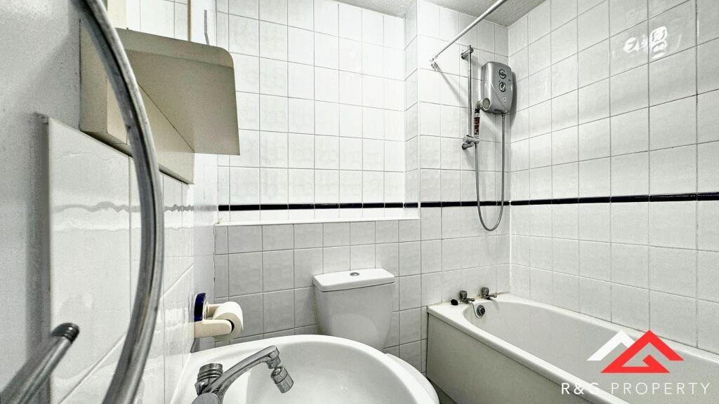 A bright and clean bathroom featuring a bathtub...