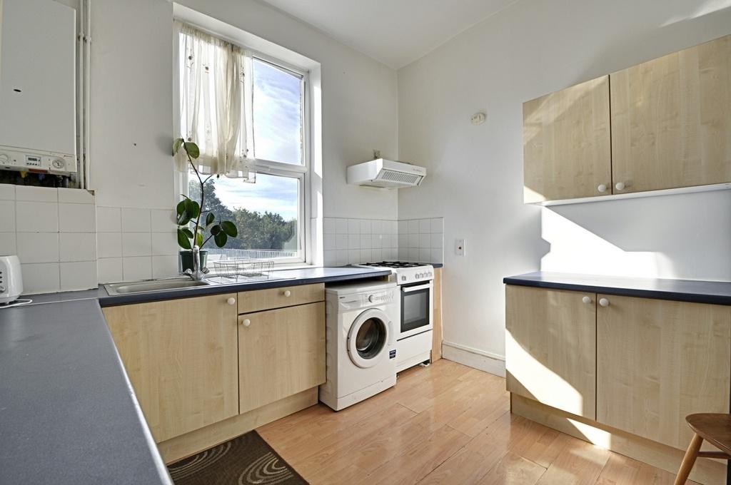 Bright and tidy kitchen featuring light wood ca...