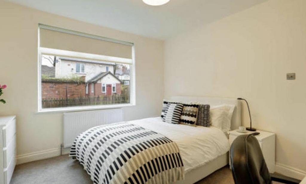 A well-lit, tidy bedroom featuring a comfortabl...