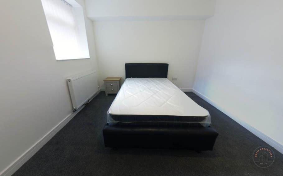 A spacious master bedroom with a comfortable be...