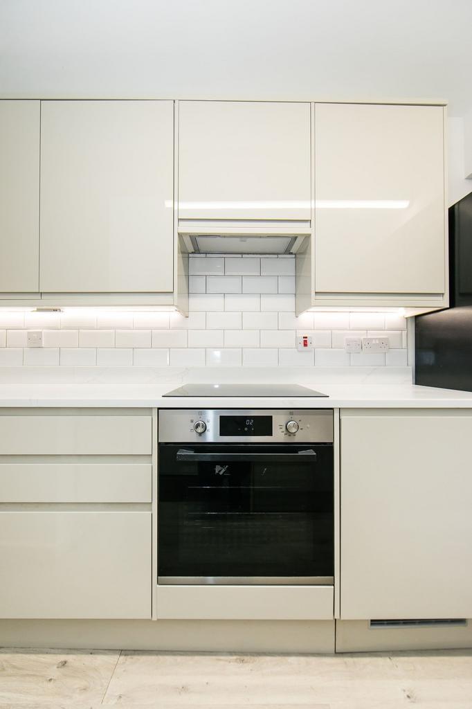 A modern, tidy kitchen featuring white cabinetr...