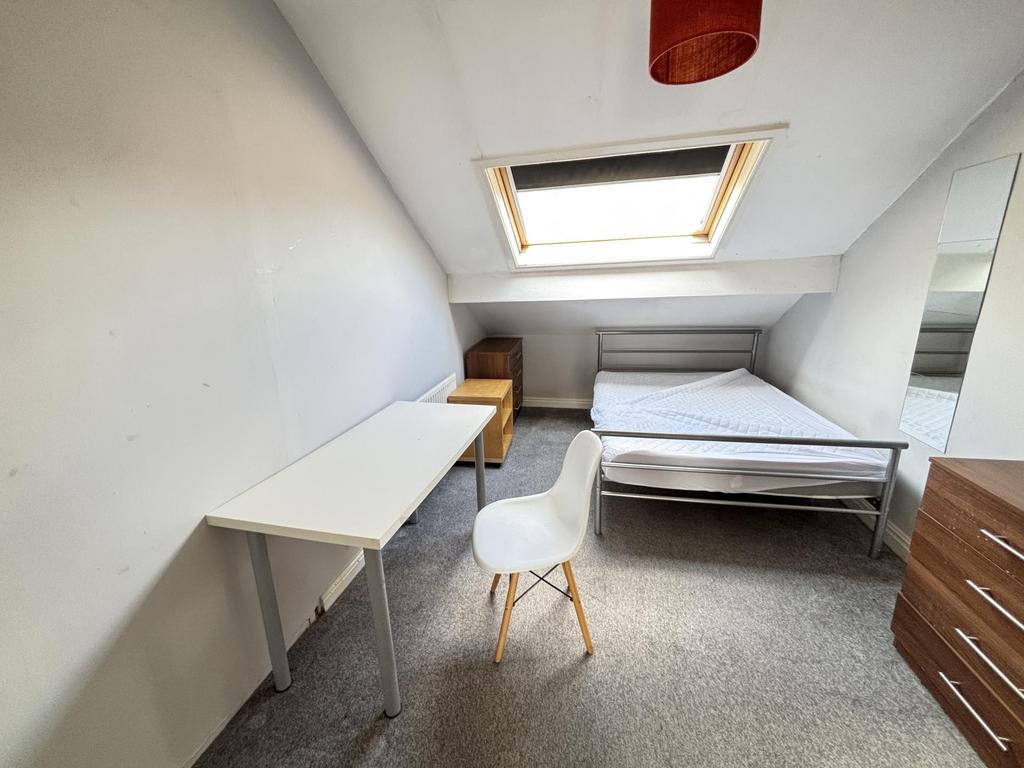 A cozy student bedroom featuring a bed and a sm...