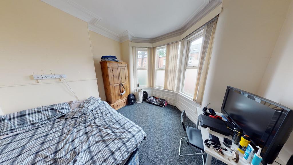 A well-lit bedroom featuring a double bed, a de...
