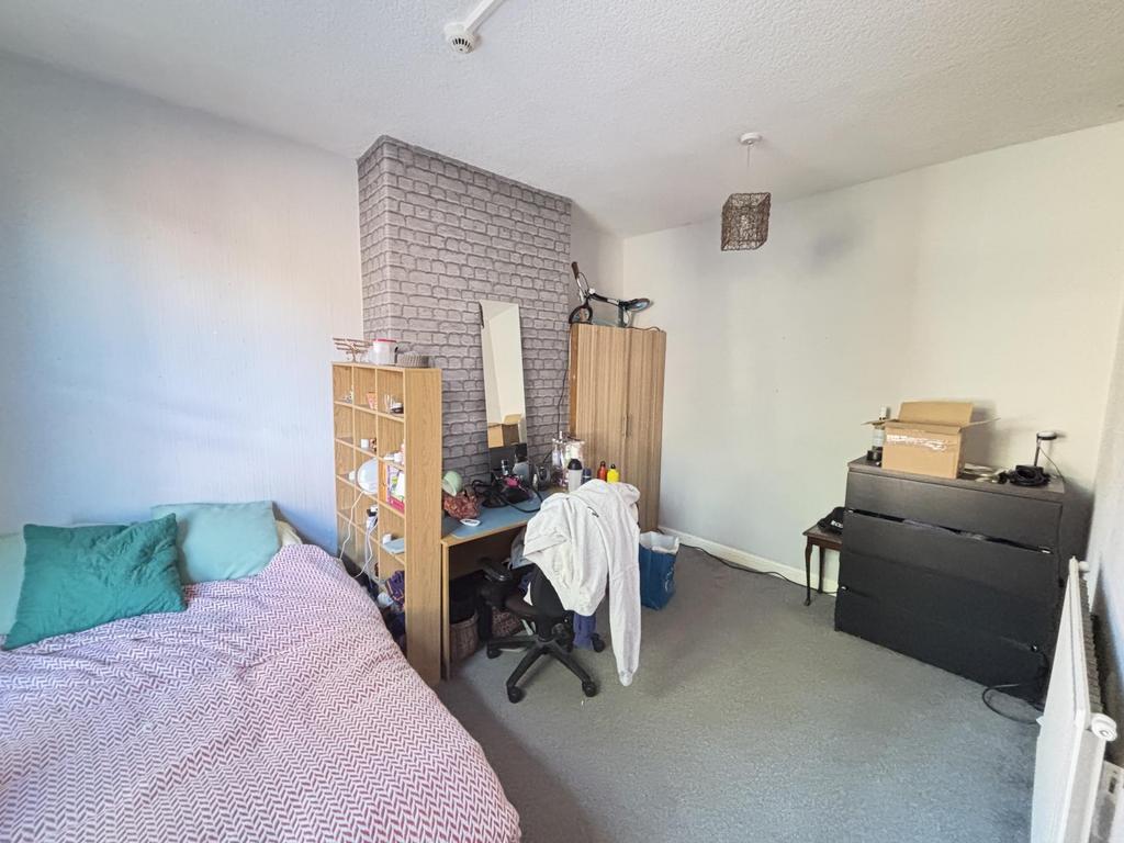 A cozy single bedroom featuring a bed with colo...