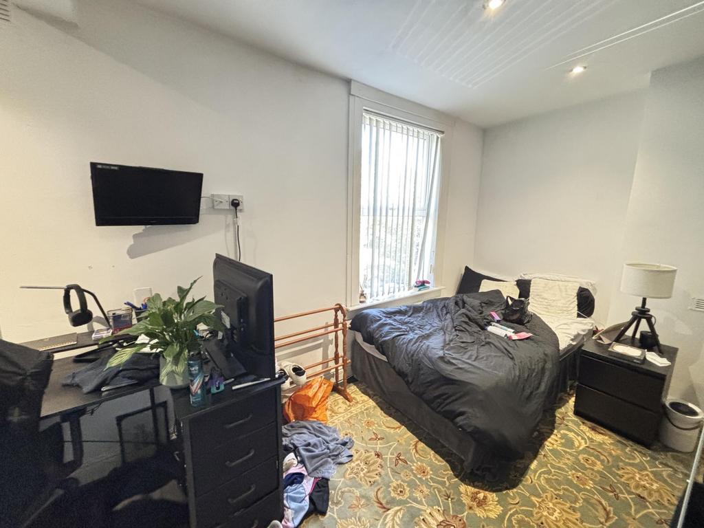 A cozy bedroom featuring a double bed, desk, an...