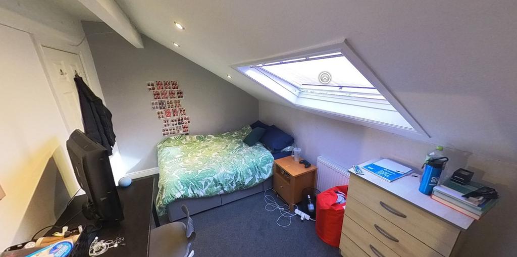A cozy single bedroom featuring a bed with bedd...