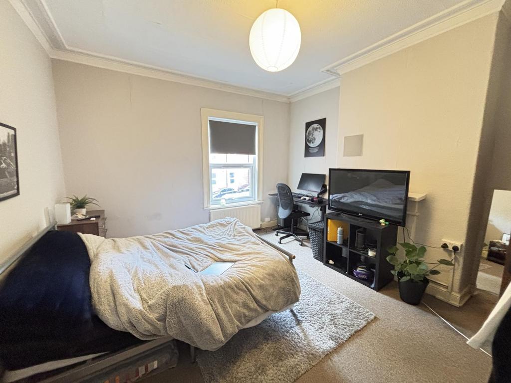 A cozy bedroom featuring a double bed, a desk w...