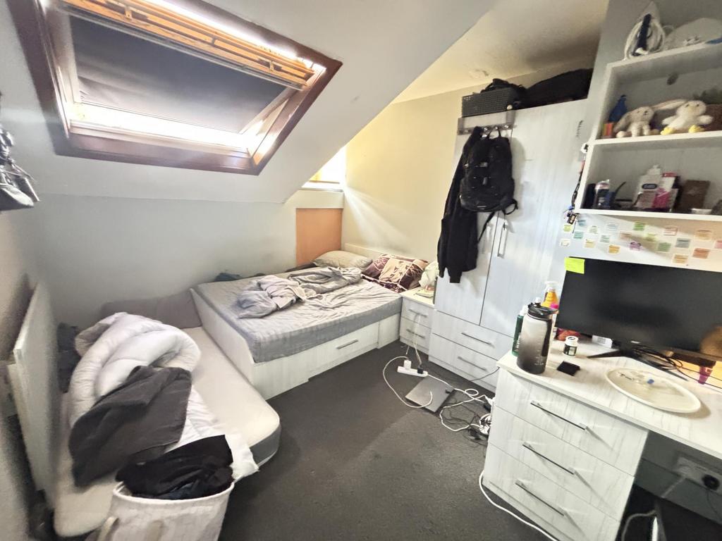 A cozy bedroom featuring a single bed, a desk, ...