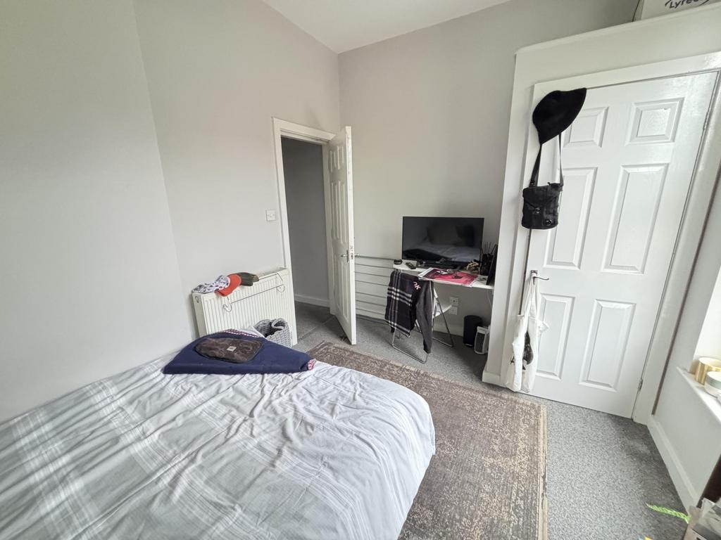 A cozy single bedroom with a neatly made bed, a...