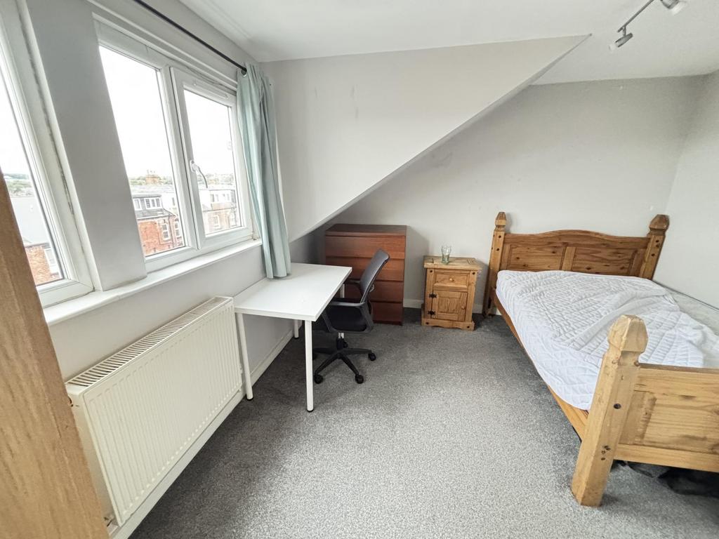 A cozy single bedroom featuring a wooden bed wi...