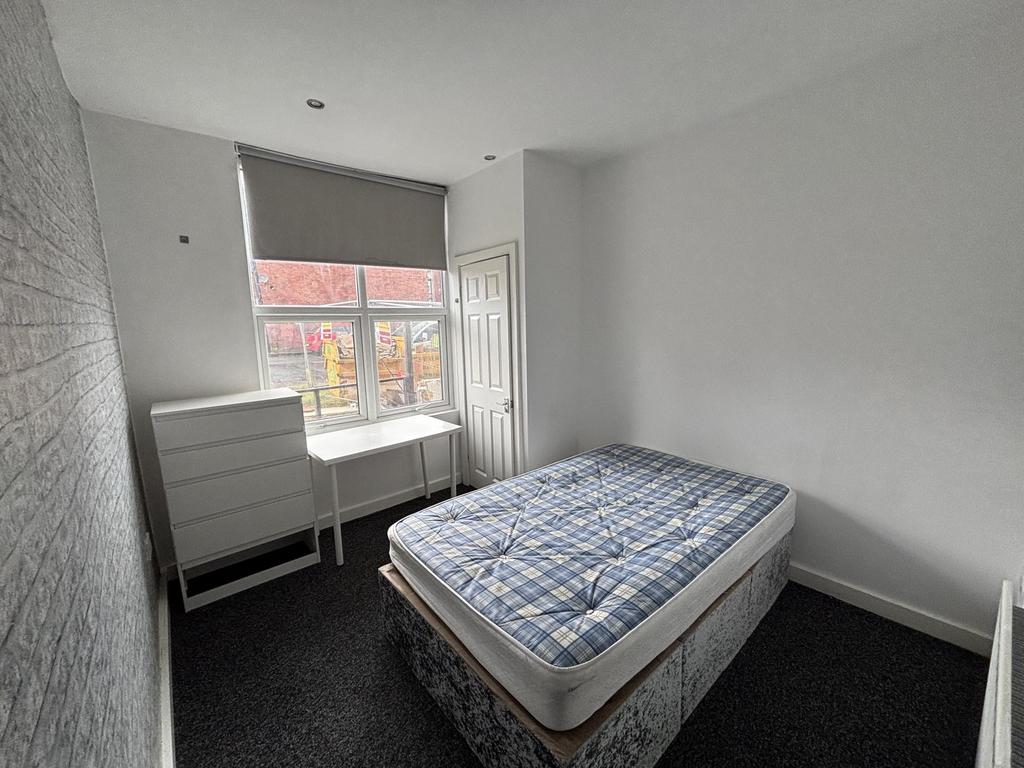 A well-lit student bedroom featuring a single b...
